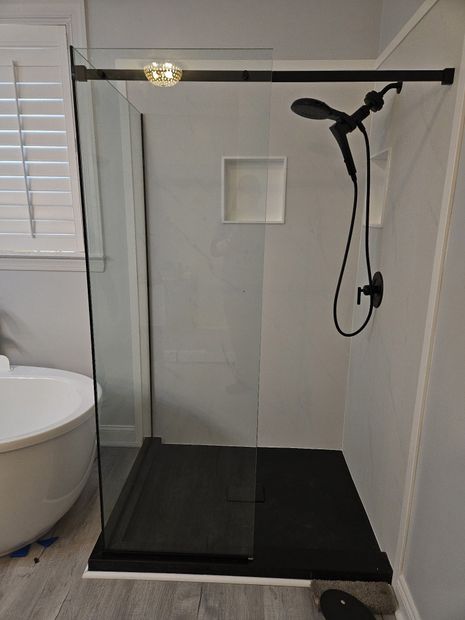 Frameless fixed-panel walk-in shower with matte black support bar and clear glass
