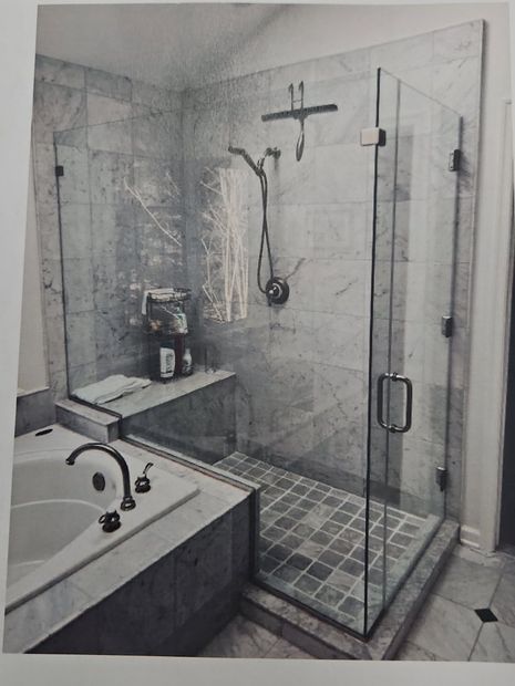 Frameless hinged corner shower enclosure with chrome hardware and a bench