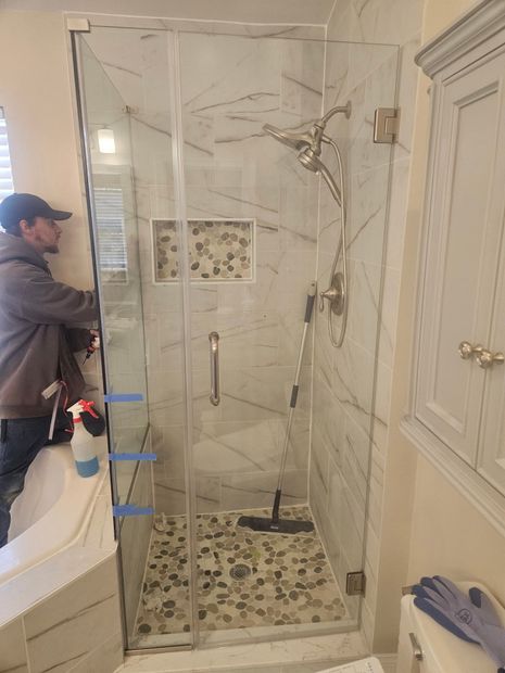 Frameless hinged shower door with marble tile and a pebble floor