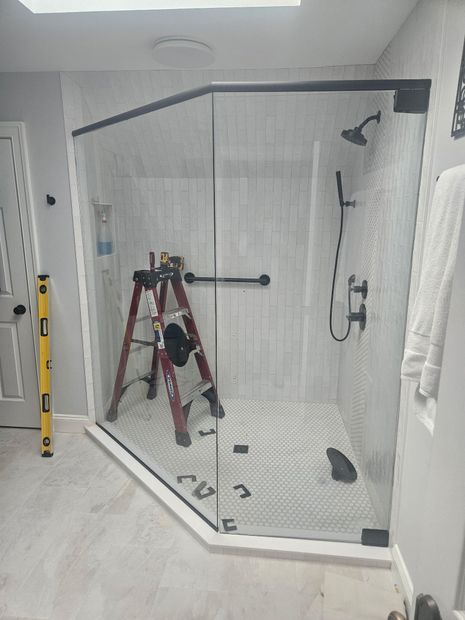 Frameless neo-angle shower enclosure with matte black header bar and white subway tile