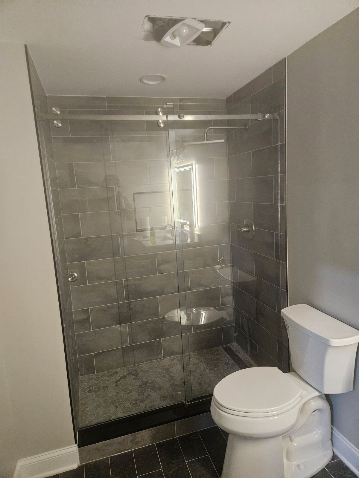 Frameless sliding shower door with clear glass and large format gray tile in Baltimore, MD