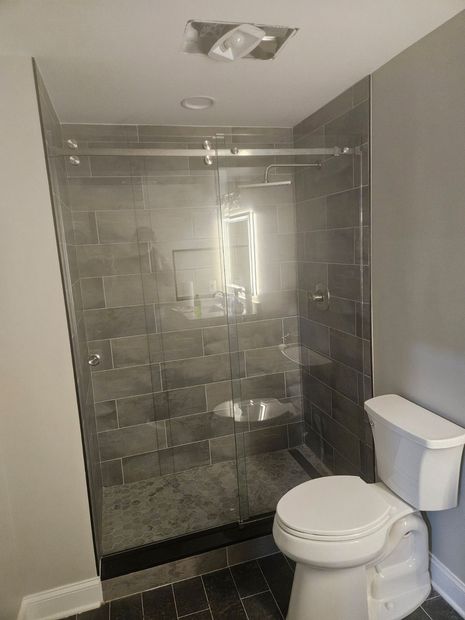 Frameless sliding shower door with large-format gray tile