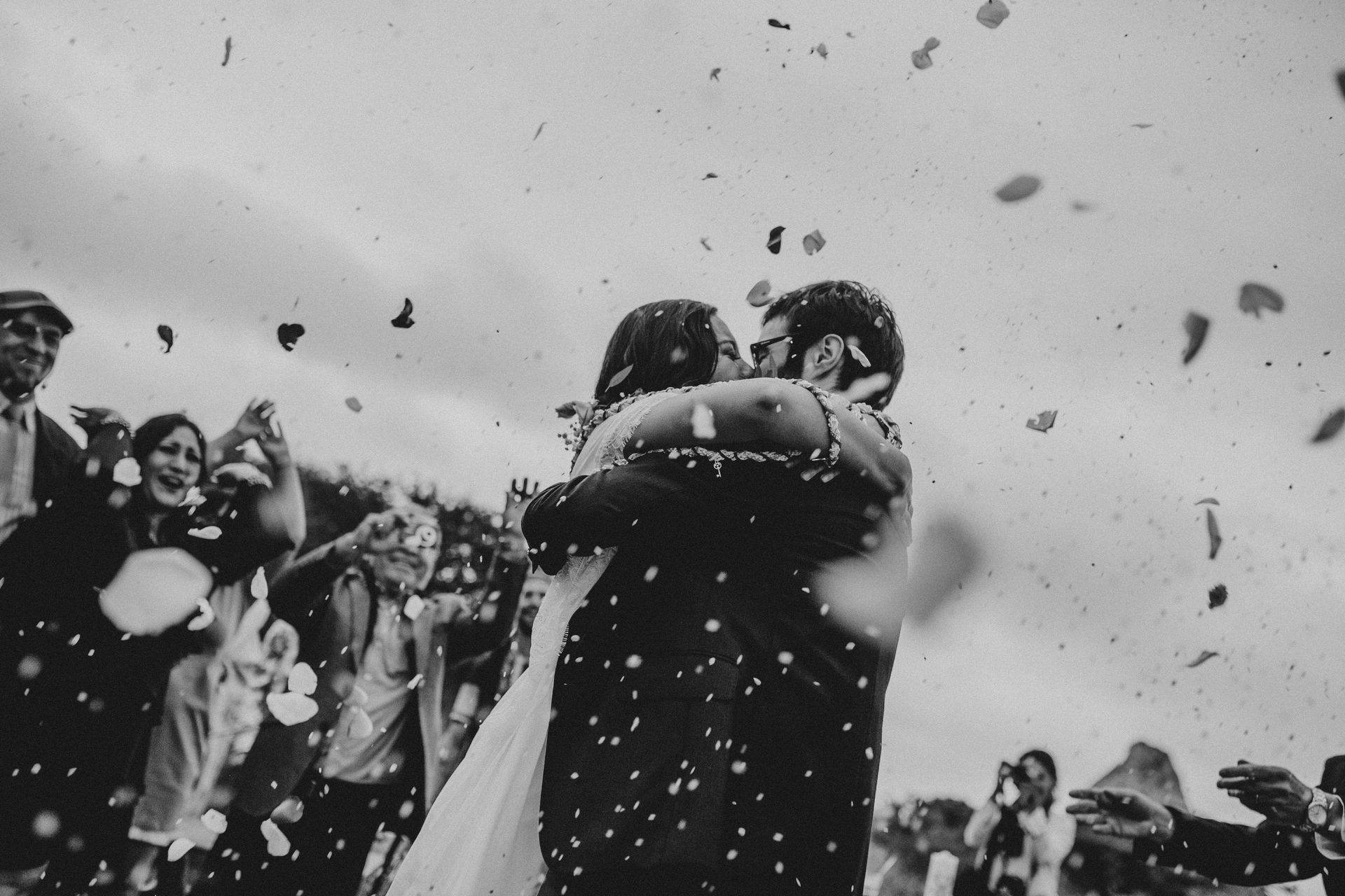 Two people embracing in a crowd as confetti falls around them.