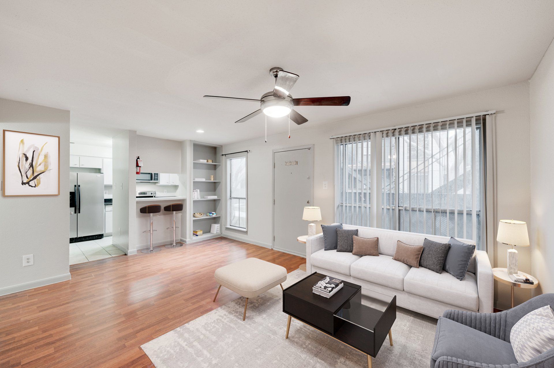 Comfortable, modern, remodeled living space in a Houston apartment with an open kitchen and ceiling fan. 
