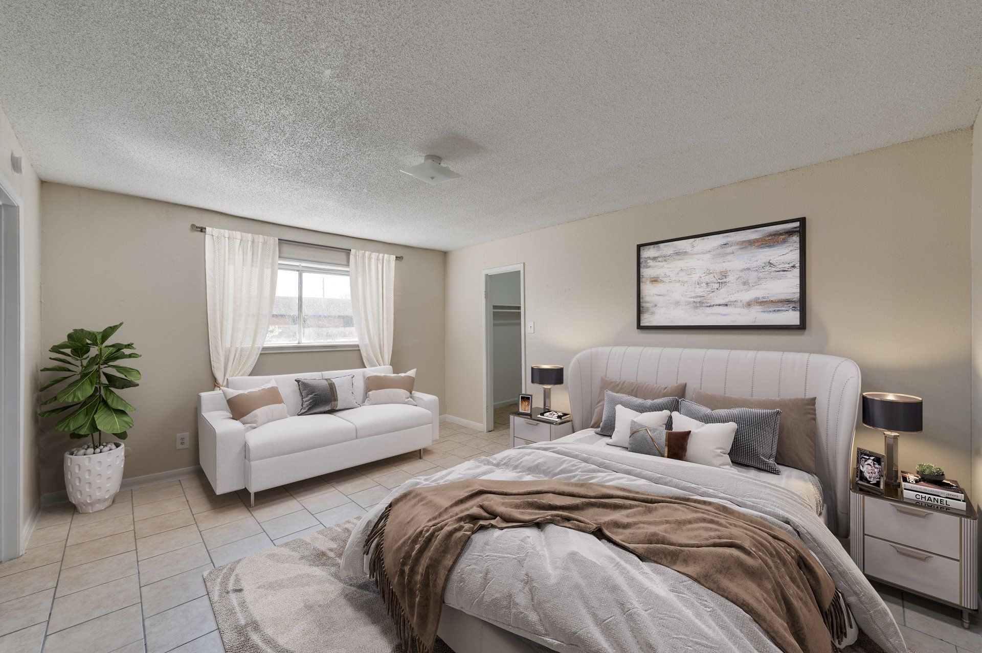Well-appointed bedroom in a Houston apartment, featuring a large bed, abstract artwork, and a stylish blue accent chair.