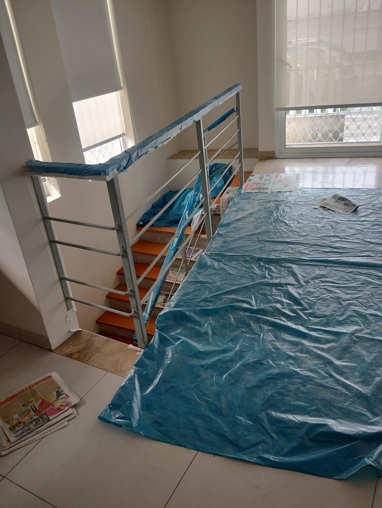 Escalera con barandilla metálica, peldaños de color naranja y cubierta protectora de color azul