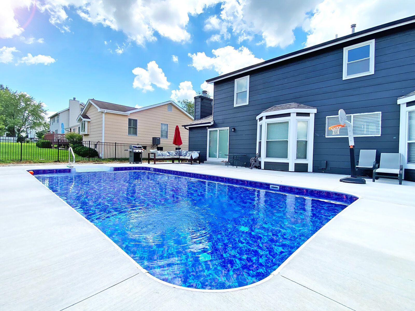 A large swimming pool is in the backyard of a house