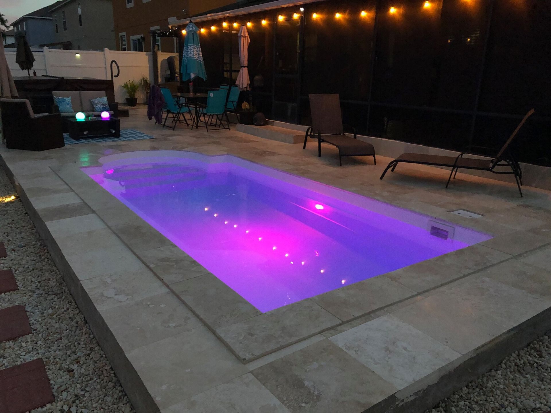 A swimming pool with purple lights on it in a backyard