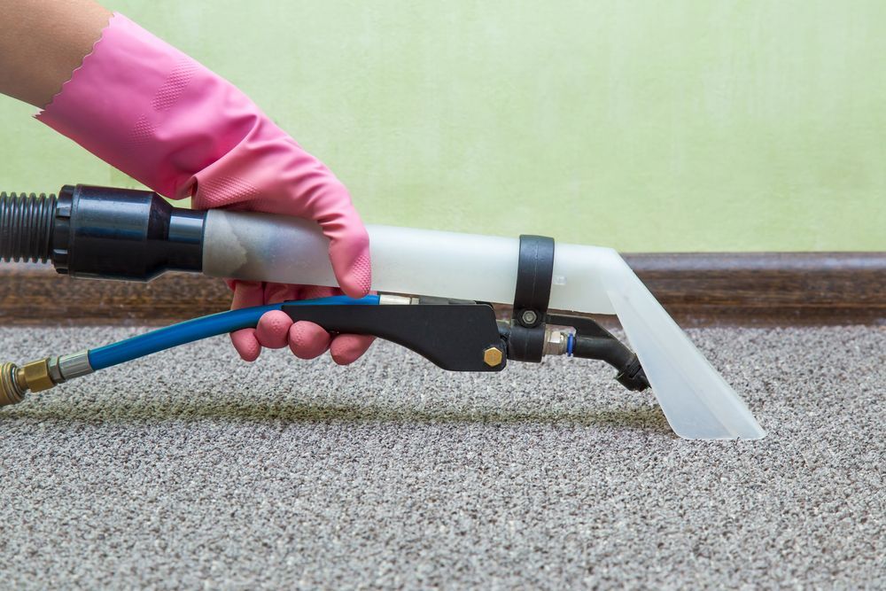 Gloved Hand Holding a Black-And-White Spray Wand to Clean Carpet — Broadbeach Carpet Cleaning In Miami, QLD