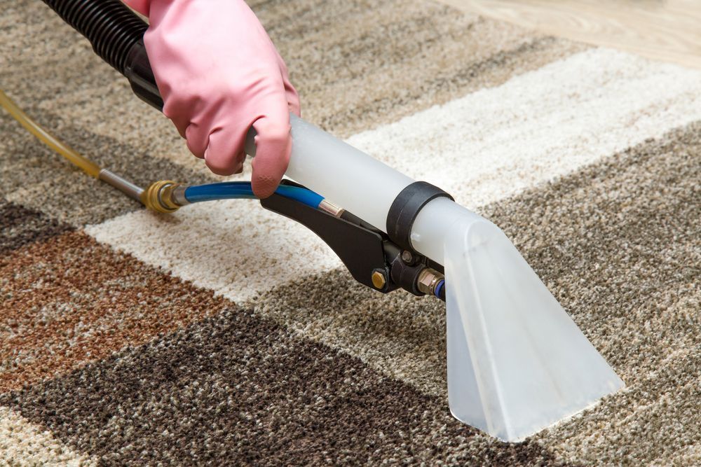 Gloved Hand Using a Carpet Cleaning Wand on A Striped Rug — Broadbeach Carpet Cleaning In Miami, QLD