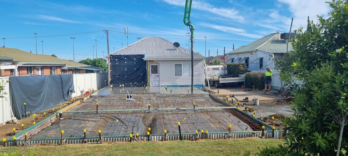 A Construction Site with A House in The Background and A Crane — Edwards & Froud Building Services Pty Ltd in Armidale, NSW