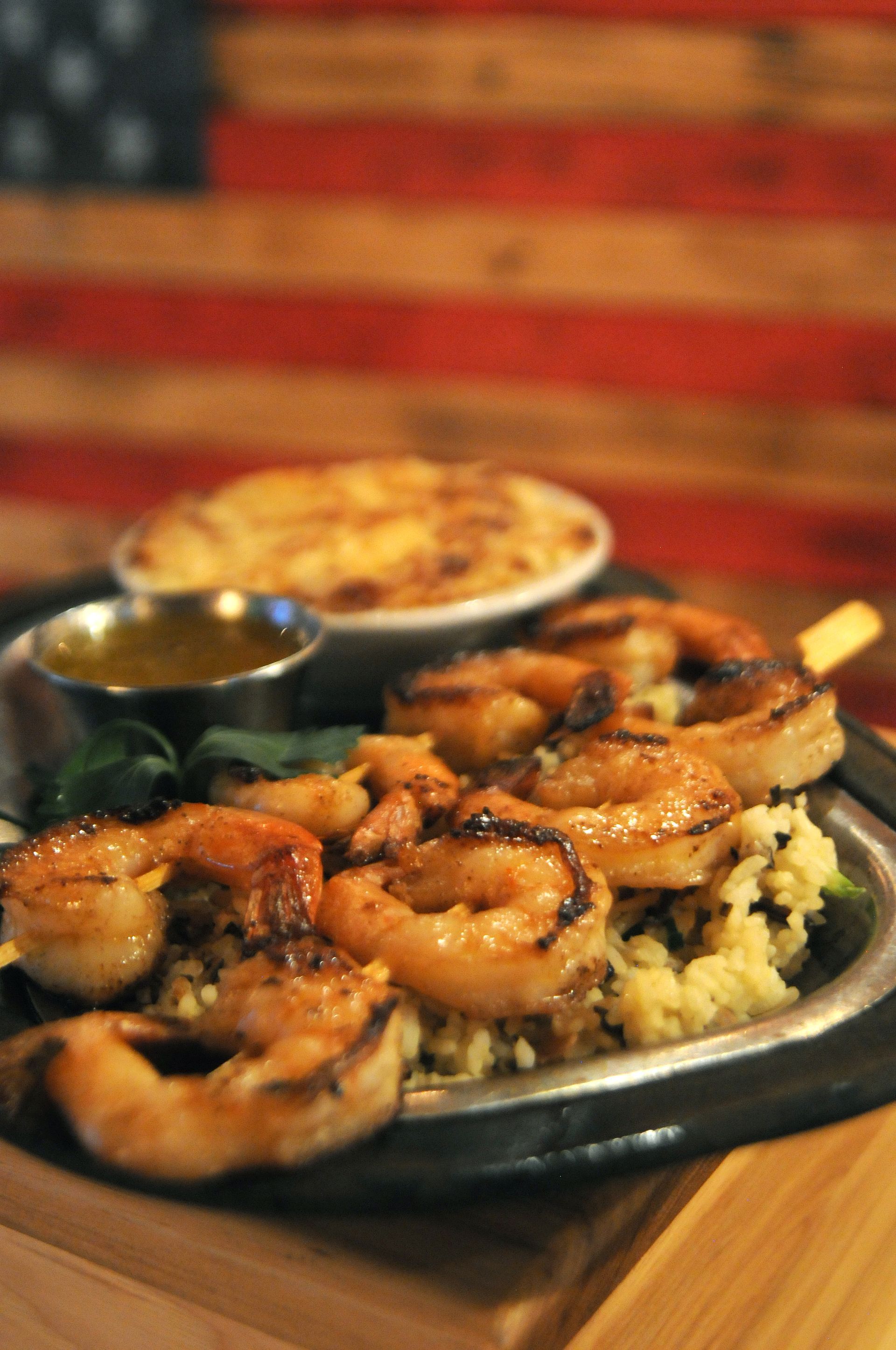 Shrimp and rice platter with sauce on a table in a warmly lit restaurant