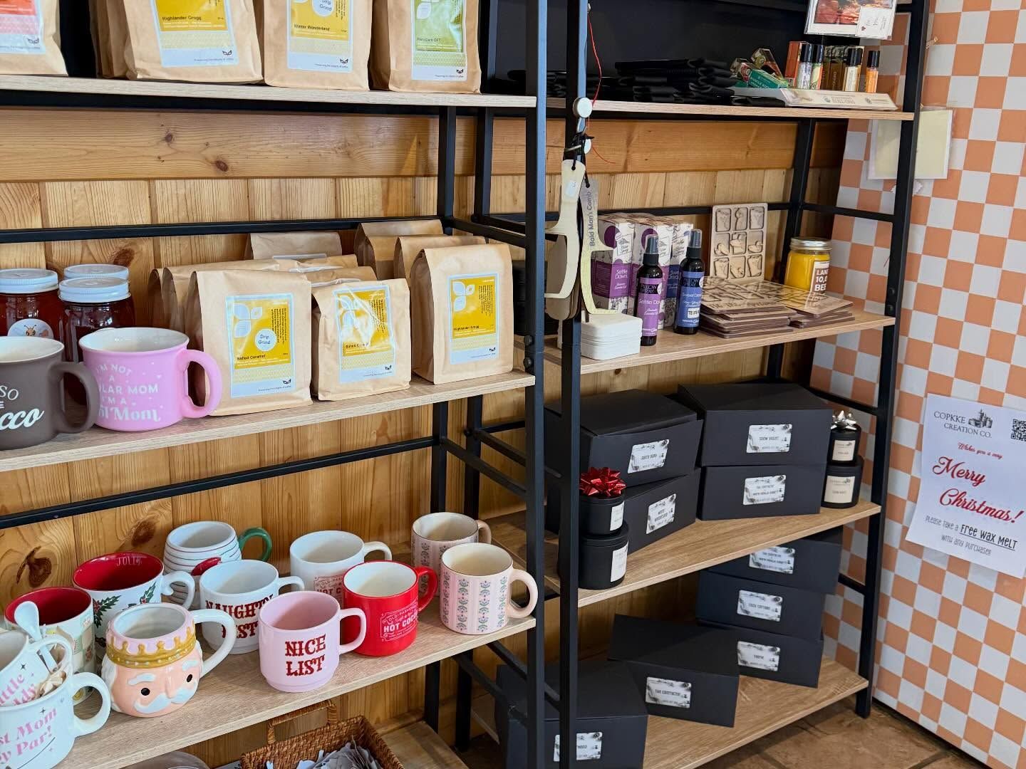 Shelves of colorful mugs, jars, and gift boxes in a cozy café-style shop display