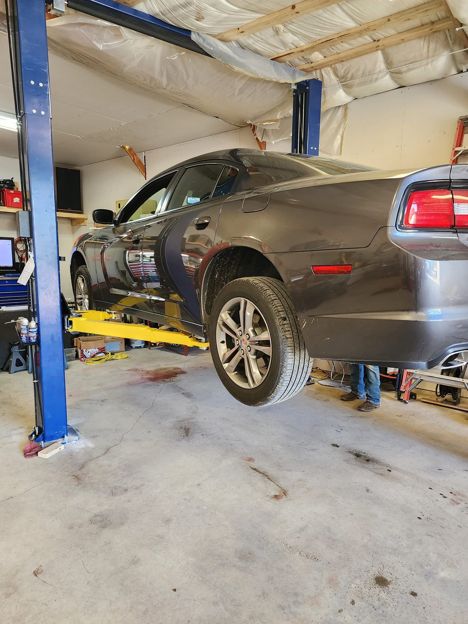 Gray car lifted on a yellow hoist inside a garage workshop