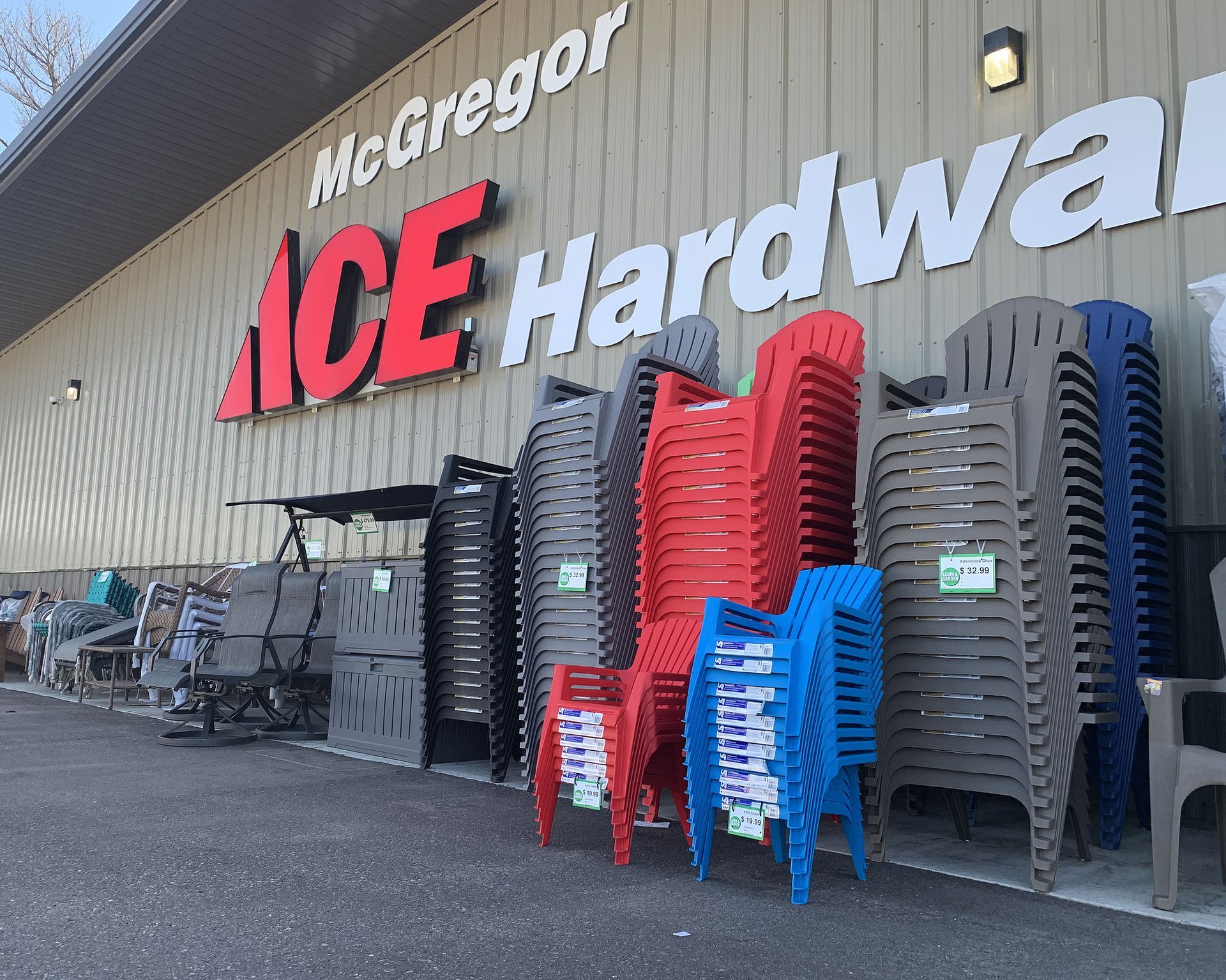 ACE Hardware storefront with stacked outdoor chairs in black, red, and blue along the entrance