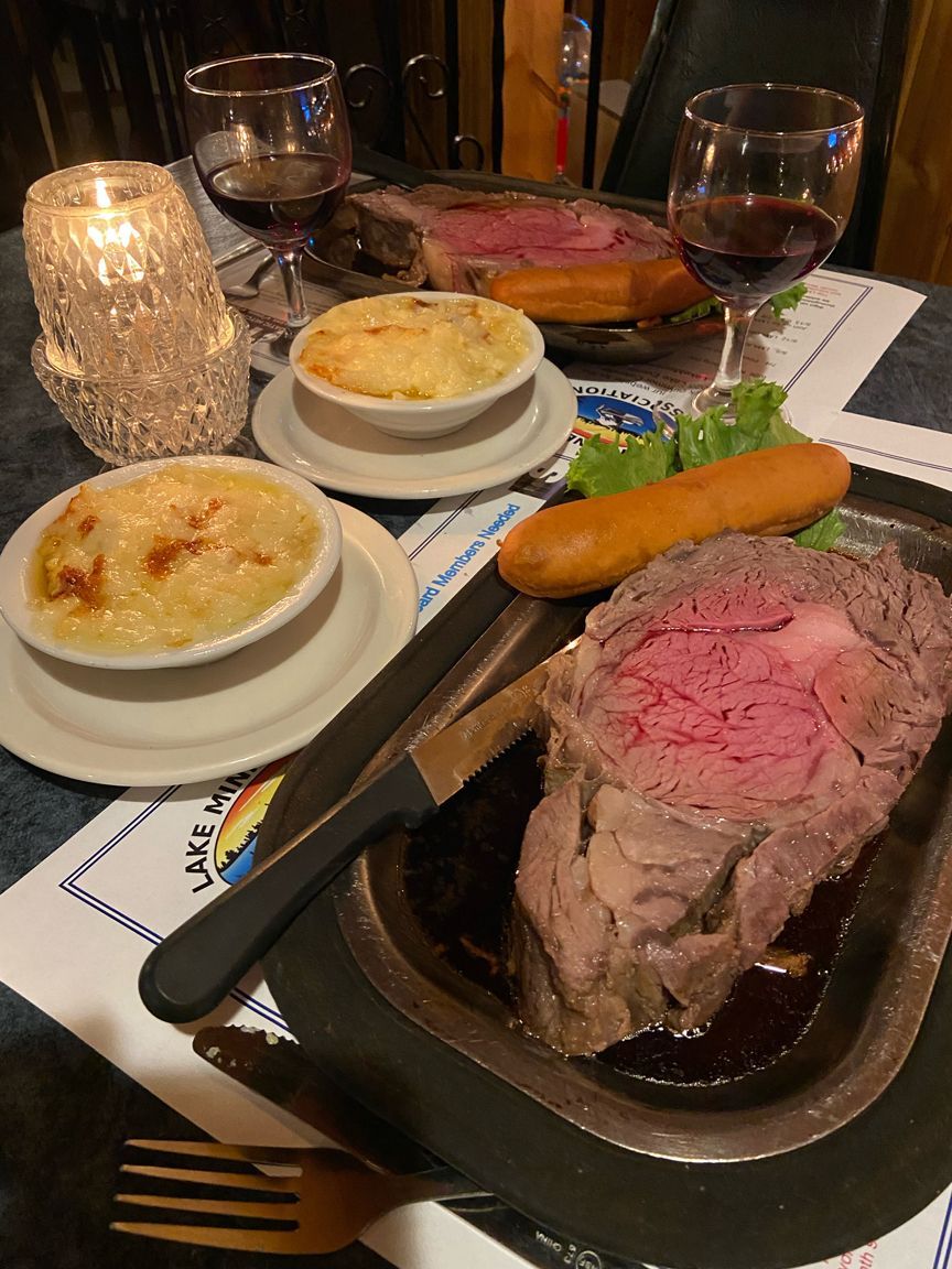 Steak dinner with mashed potatoes, vegetables, and drinks on a restaurant table