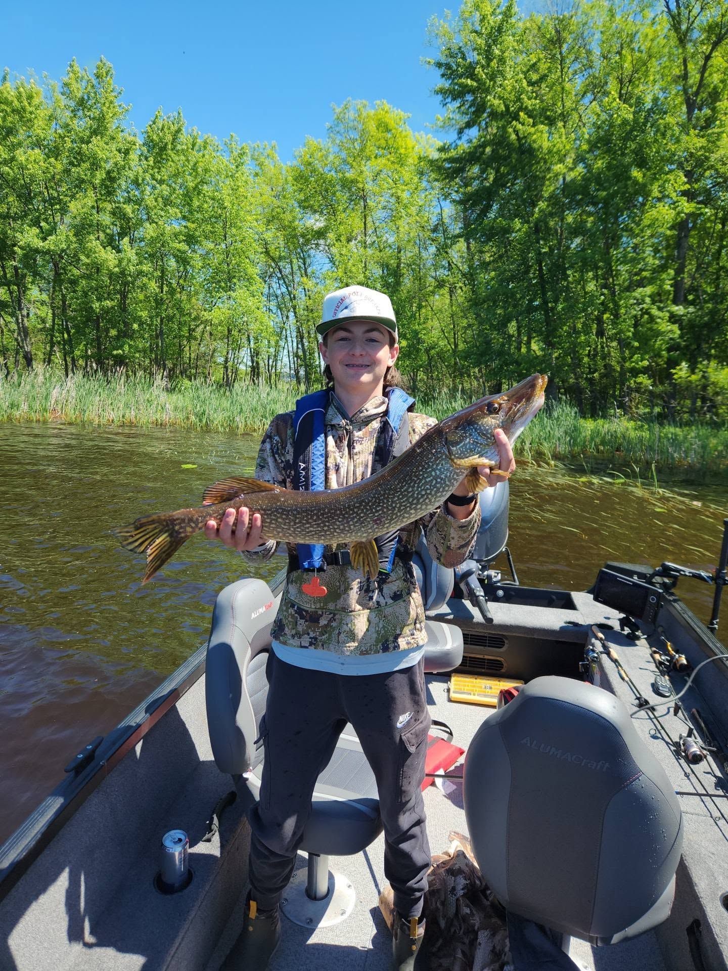 Person holding a large fish on a boat in a wooded river