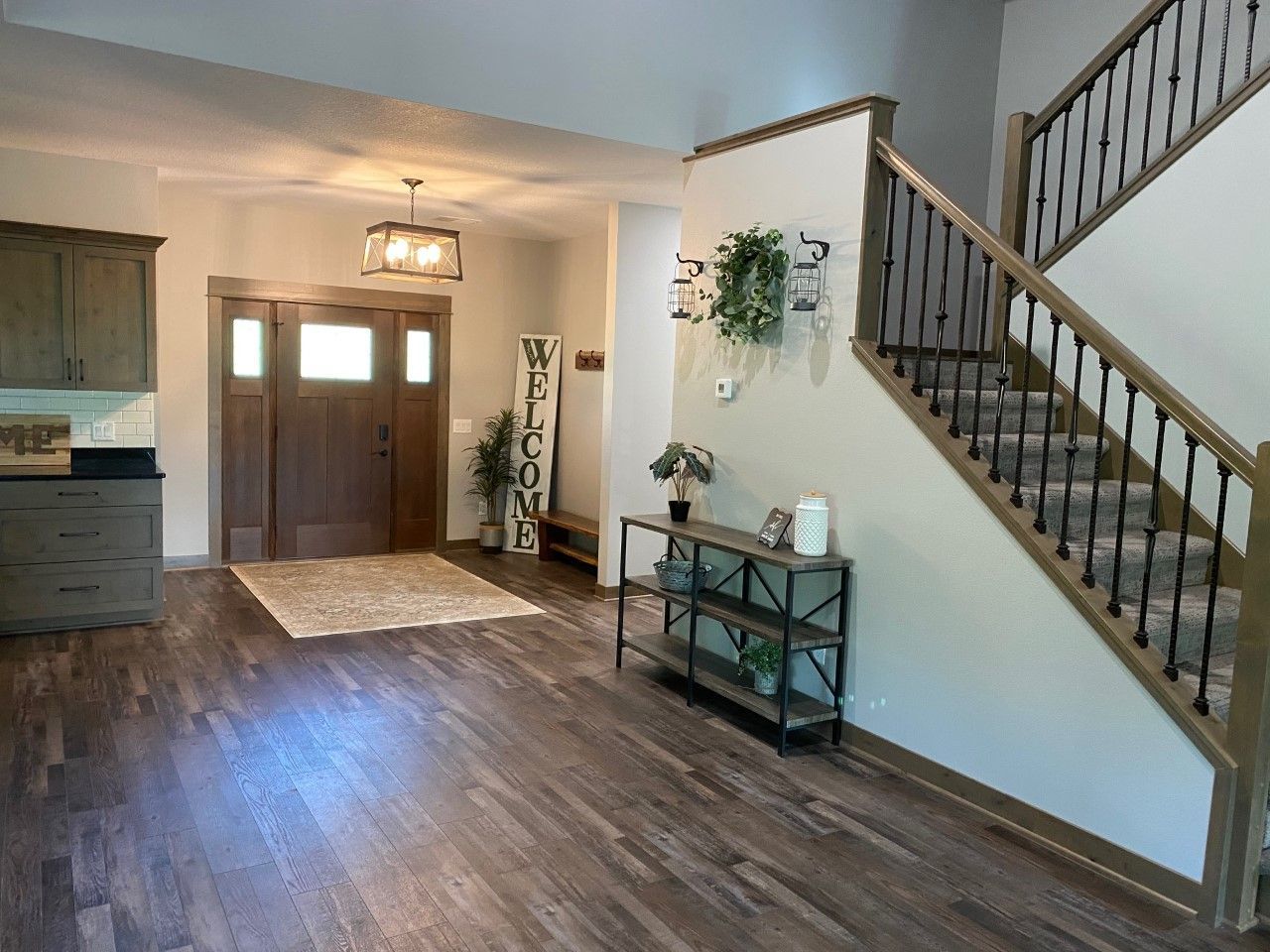 Entryway with wood floors, front door, staircase, and a small console table with decor.