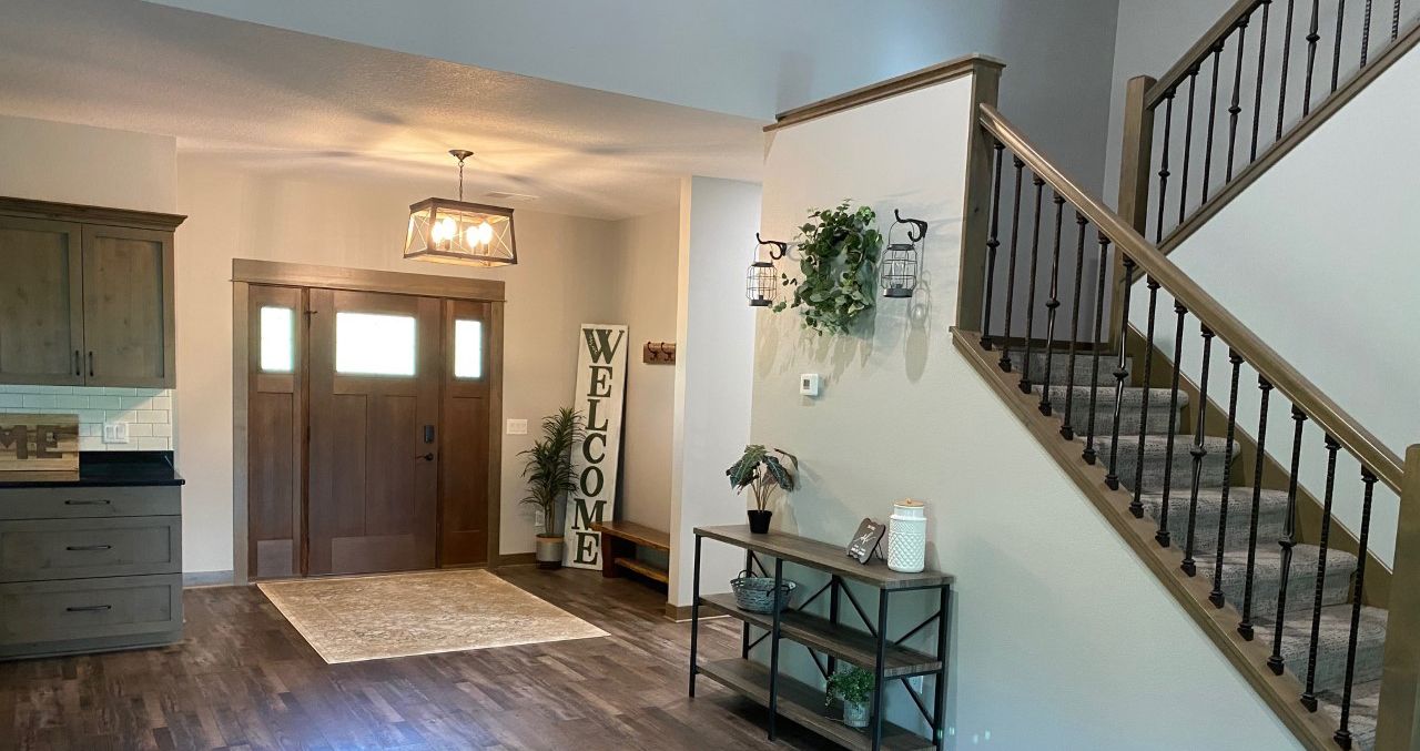 Spacious foyer with double front doors, staircase, console table, and hardwood floors.