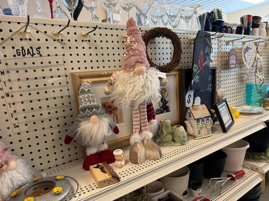 Craft store shelf with handmade gnome dolls and wreaths displayed on a pegboard wall
