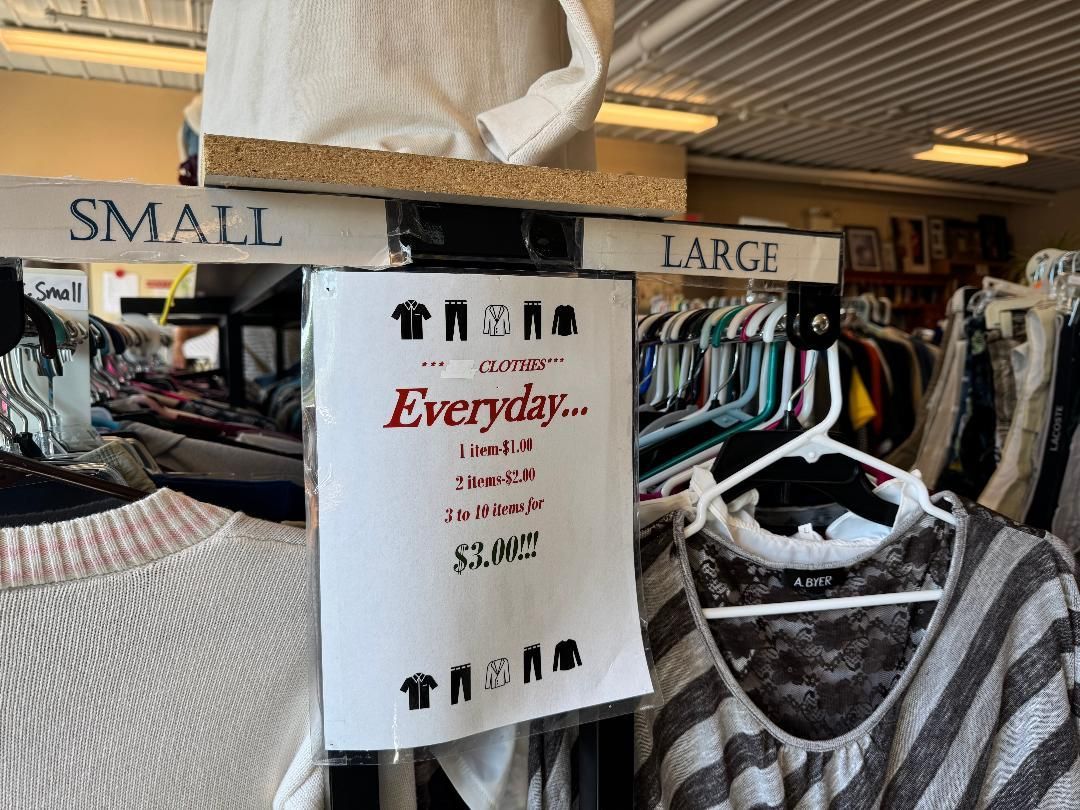 Clothing store racks labeled small and large, with a white “Everything” sale sign in the center