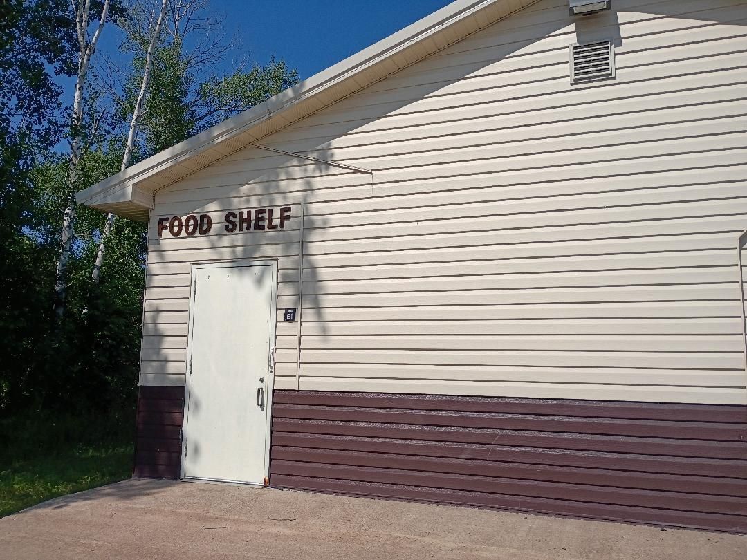 Side view of a beige building with a sign reading “Food Shelf” above the entrance.