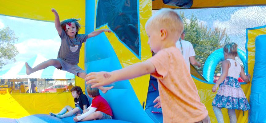 Children playing on colorful inflatable slides and obstacles at an outdoor play area