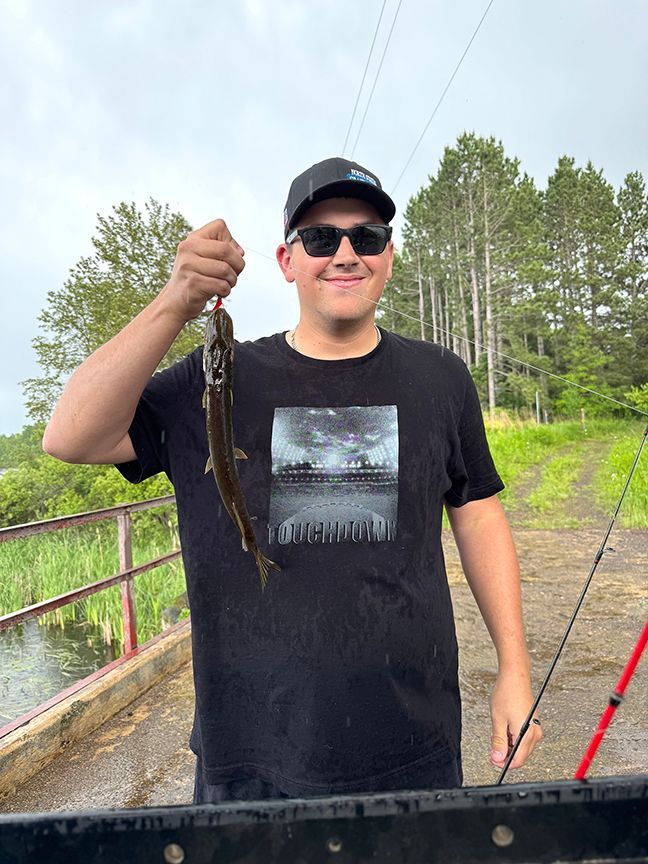 A boy holding a Northern Pike caught on Woodbury Lake