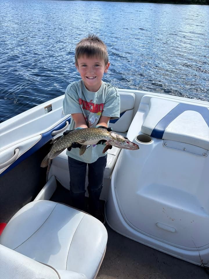 Boy holding a fish on a boat with blue water in the background