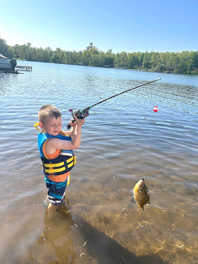 A boy holding a fishing rod with a Sunfish caught on Eagle Lake