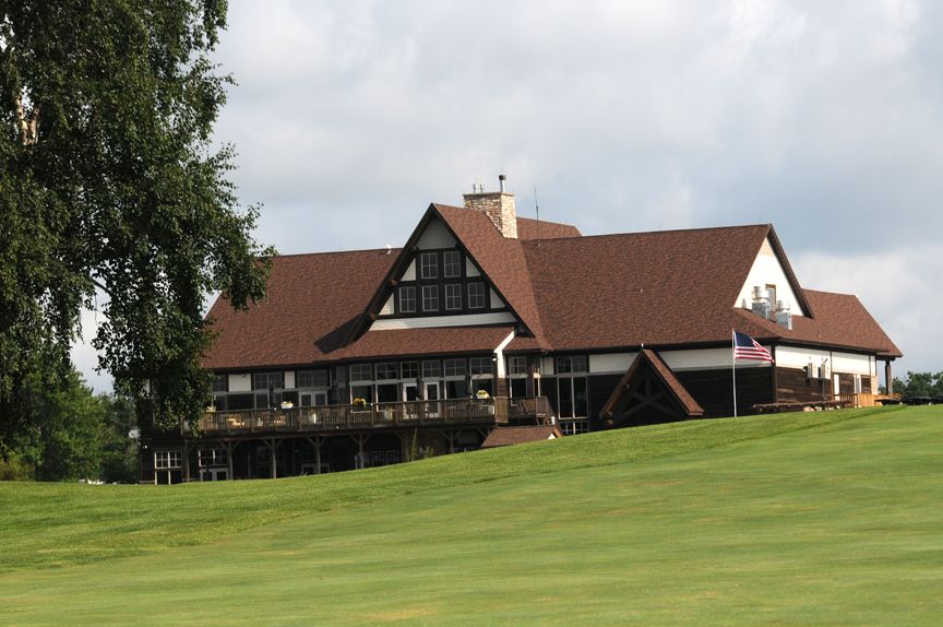 Large lodge with red roofs on a green hillside under a cloudy sky