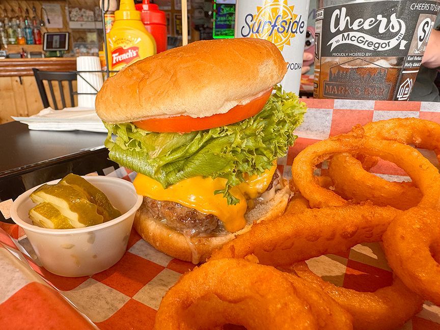Smash burger with lettuce and tomato and a side of onion rings