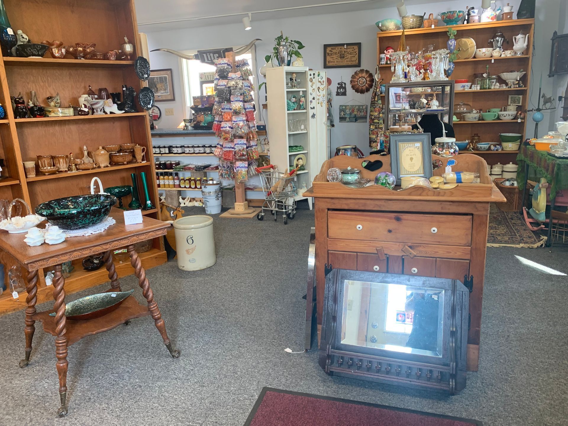 Antique shop interior with wooden shelves, tables, and a fireplace insert in the foreground
