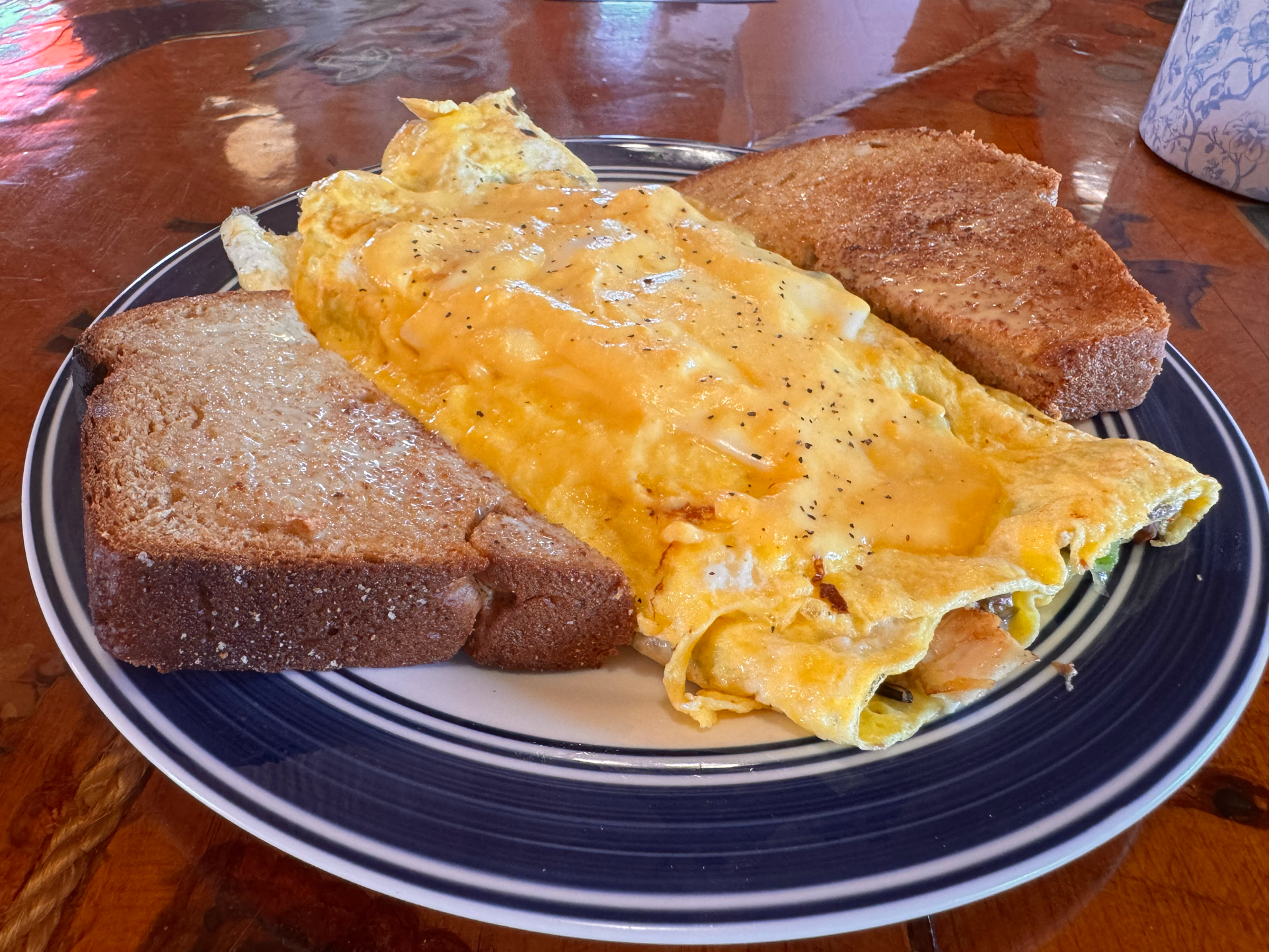 Wild Rice omelet on a blue plate with two slices of toast on a wooden table