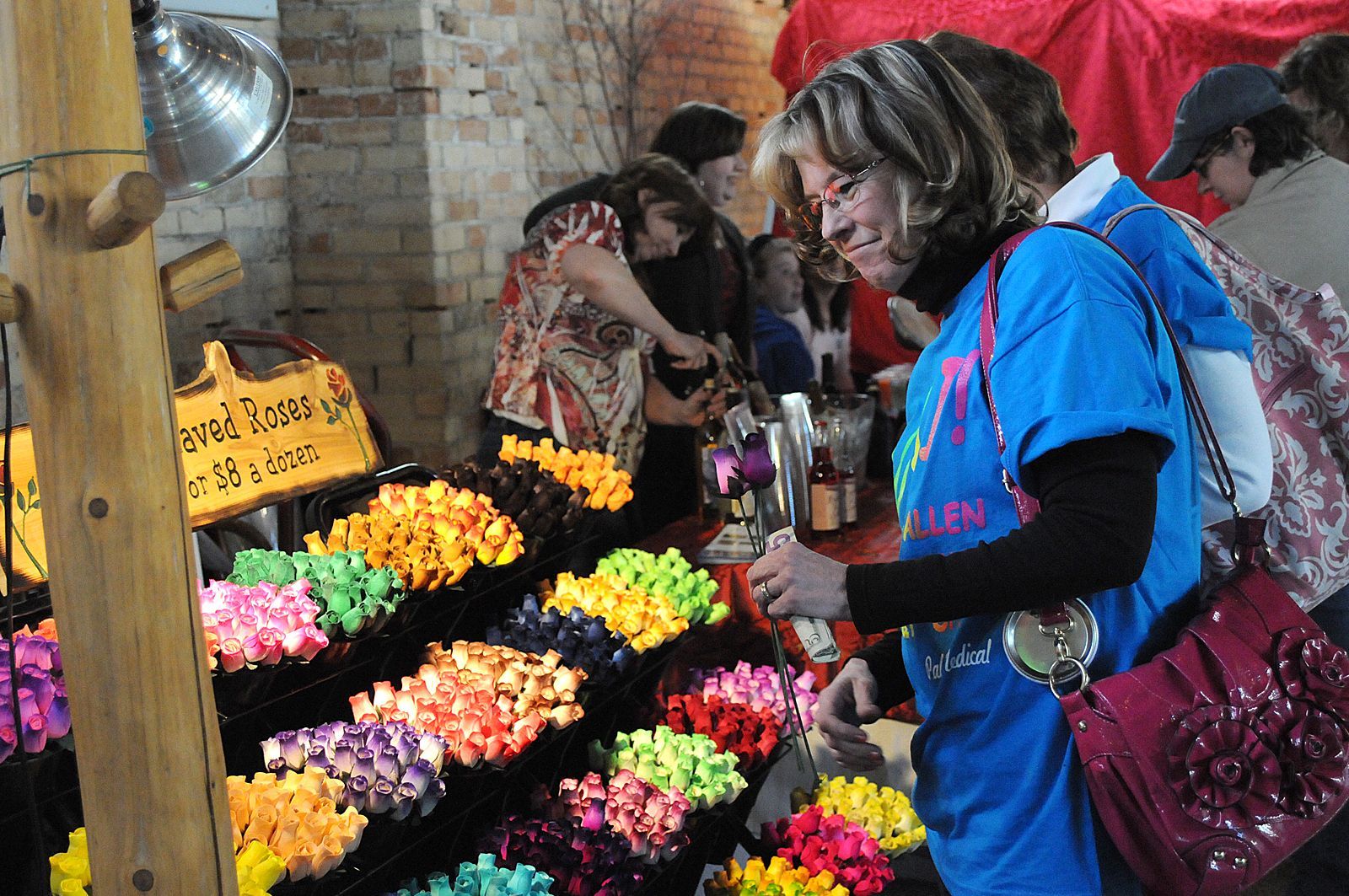 People browsing colorful flower bouquets at a market stall
