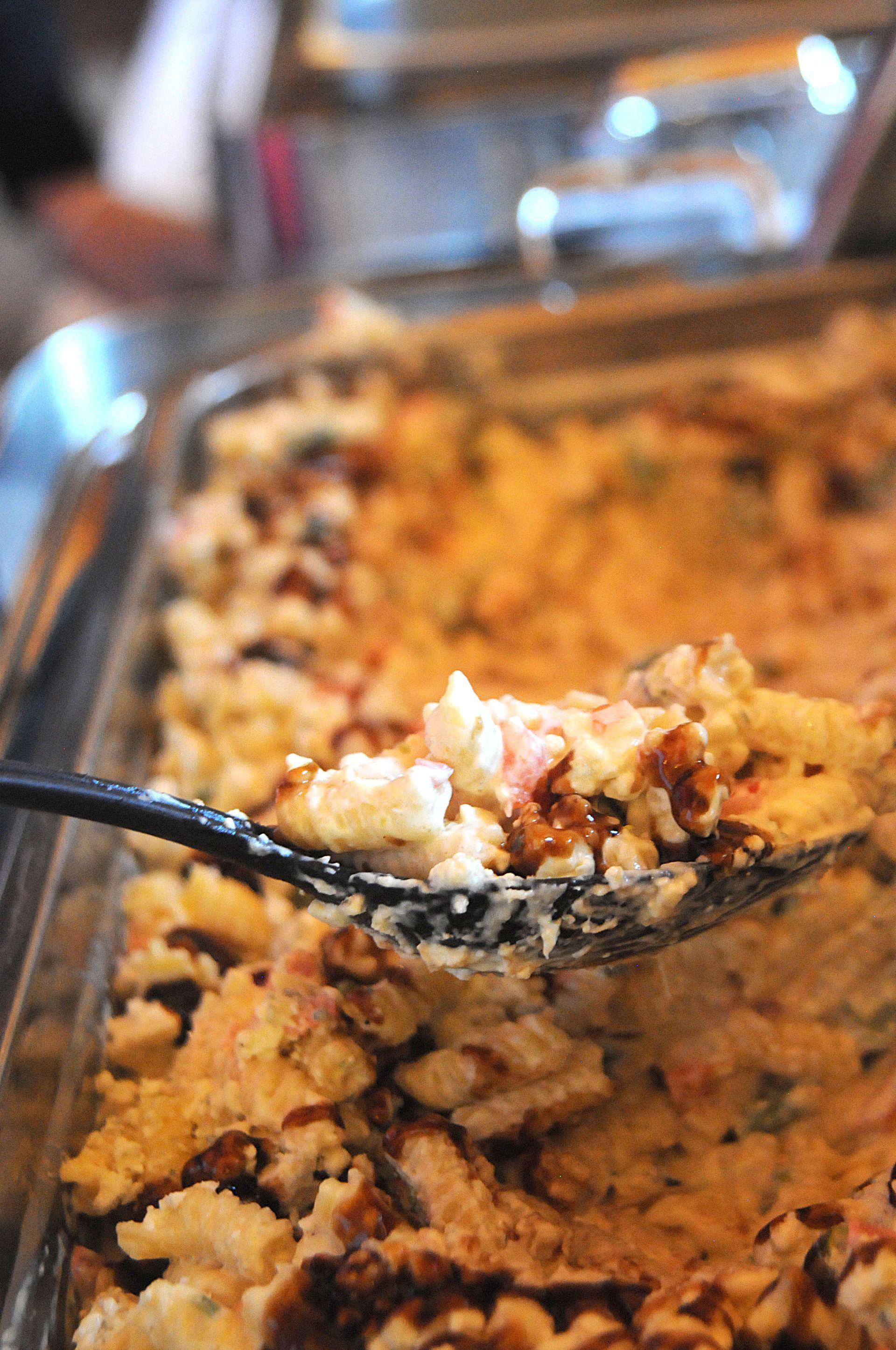 Spoon lifting a scoop from a baked casserole in a foil baking dish
