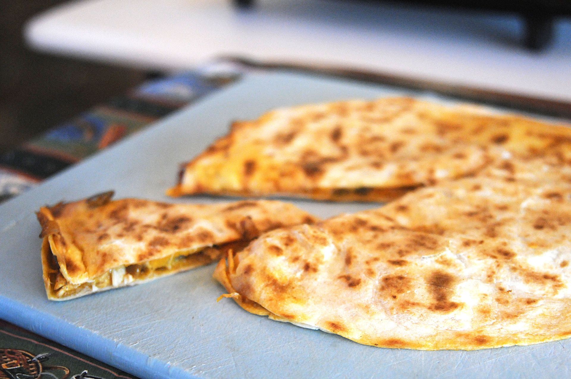 Sliced cheese pizza on a baking tray, with one slice lifted