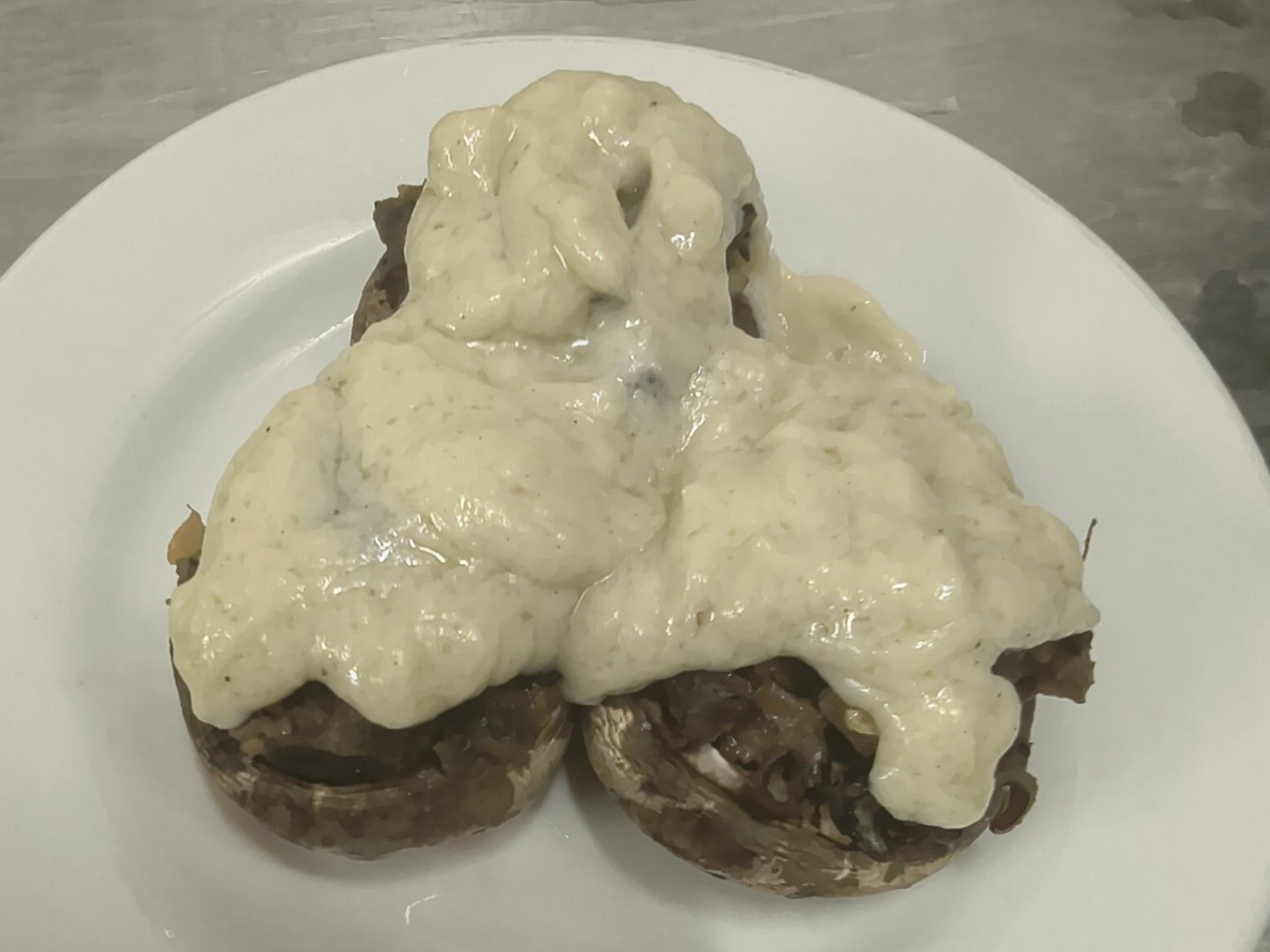 Two meat patties topped with melted white cheese on a white plate.