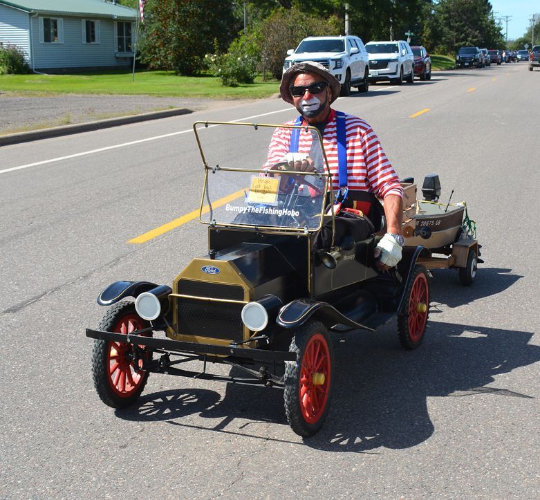 Man in helmet and sunglasses driving a homemade mini car on a sunny suburban street