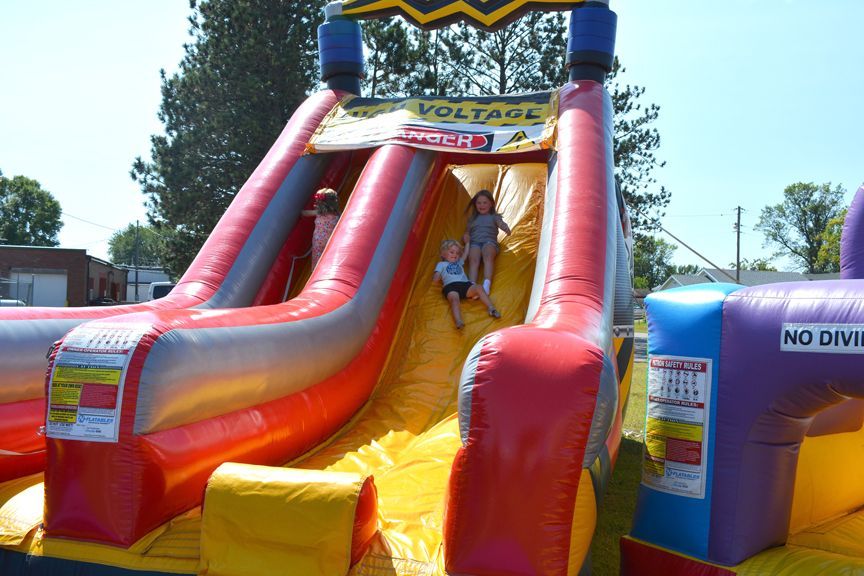 Colorful inflatable slide with a child climbing down outdoors on a sunny day