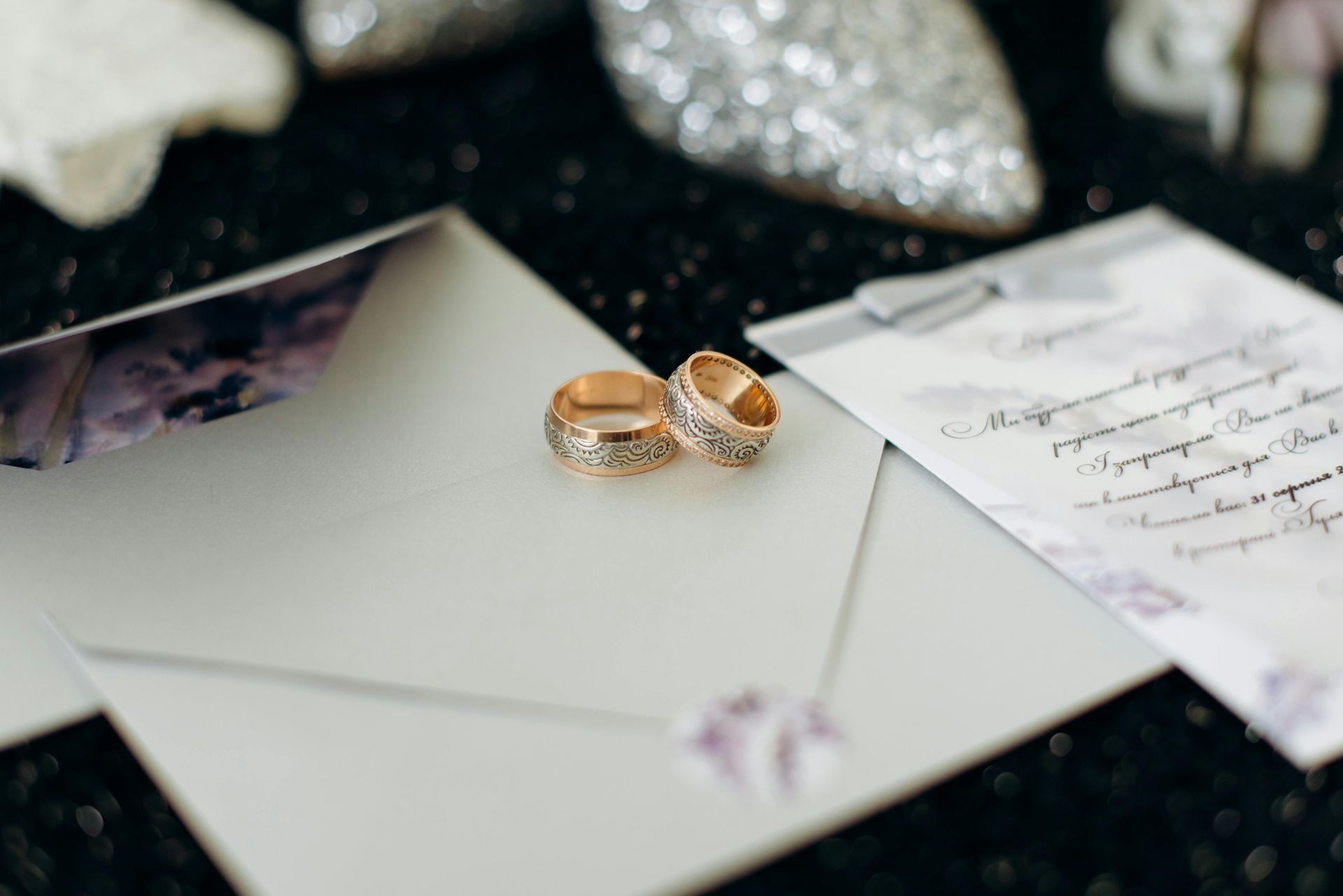 Wedding rings on a handwritten invitation with envelopes and glittering decor