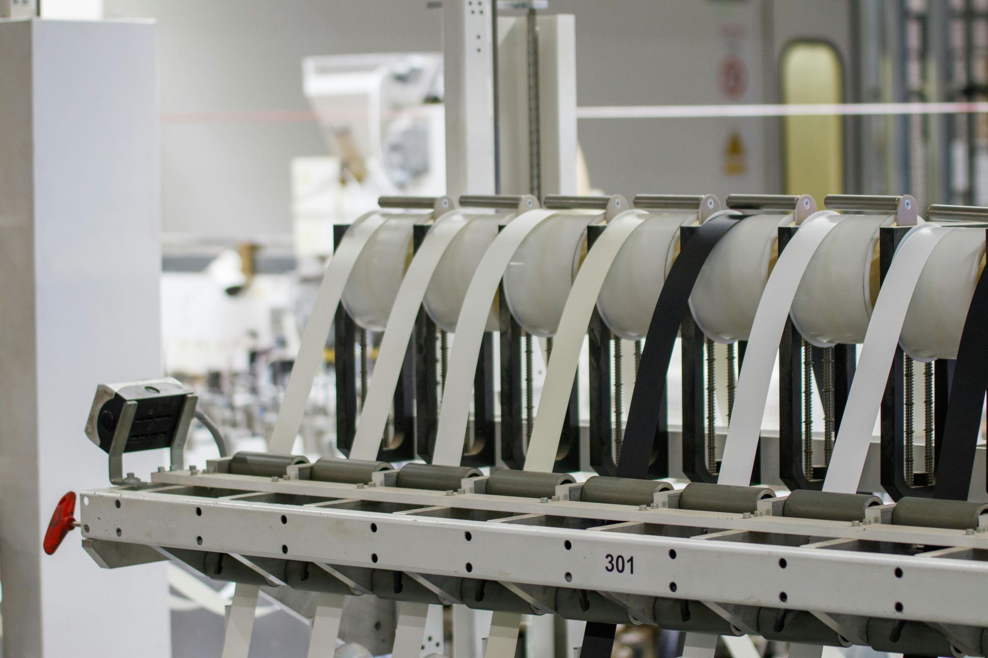 Industrial machine with rows of white curved components on a production line in a factory-like setting