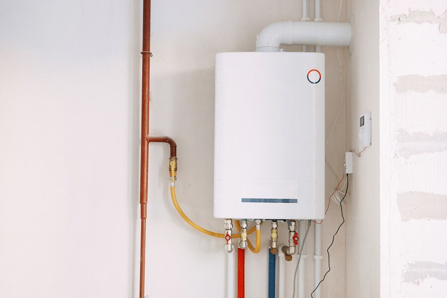 Wall-mounted white boiler with copper and yellow pipes in a utility room
