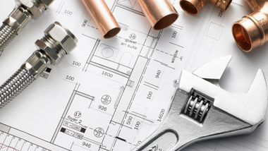 Plumbing tools, copper pipes, and fittings on a technical blueprint