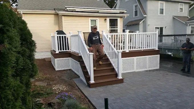 A man is standing on a deck next to a house.