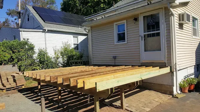 A wooden deck is being built in front of a house.