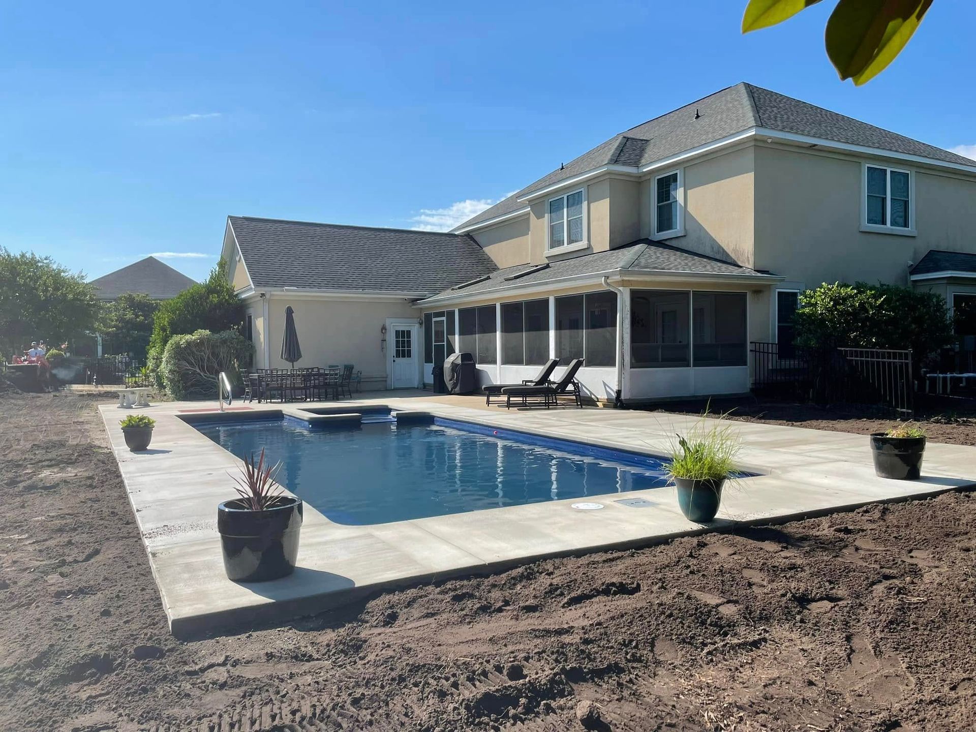 Backyard with a rectangular swimming pool beside a two-story house and patio lounge chairs