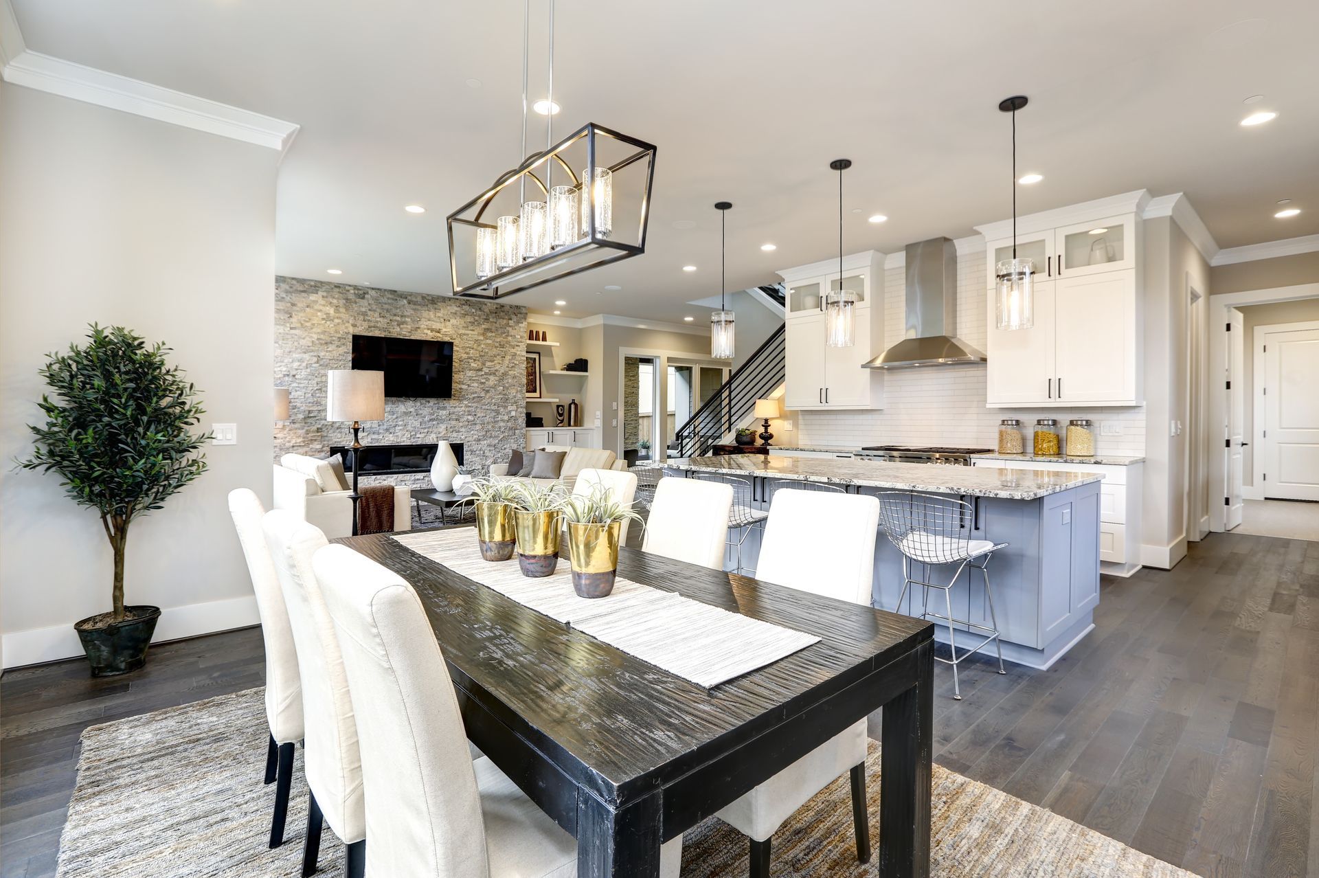 Bright modern open-plan kitchen and dining room with island, white cabinets, and dark wood floors Bright modern open-plan kitchen and dining room with island, white cabinets, and dark wood floors