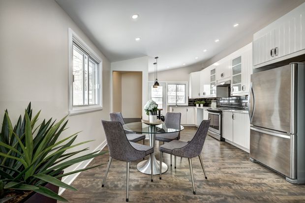 Modern kitchen with white cabinets, stainless appliances, island, dining table, and large windows