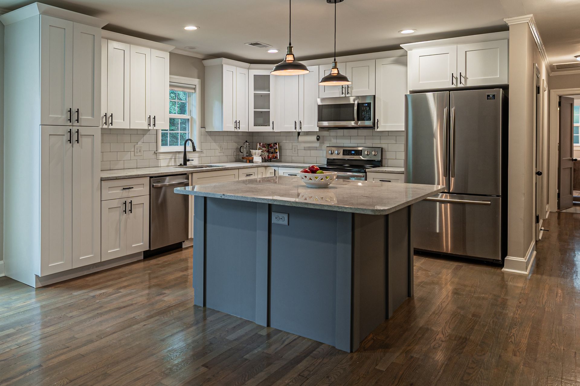 Modern kitchen with stainless steel appliances, white cabinets, and a large island with granite countertop Modern kitchen with stainless steel appliances, white cabinets, and a large island with granite countertop